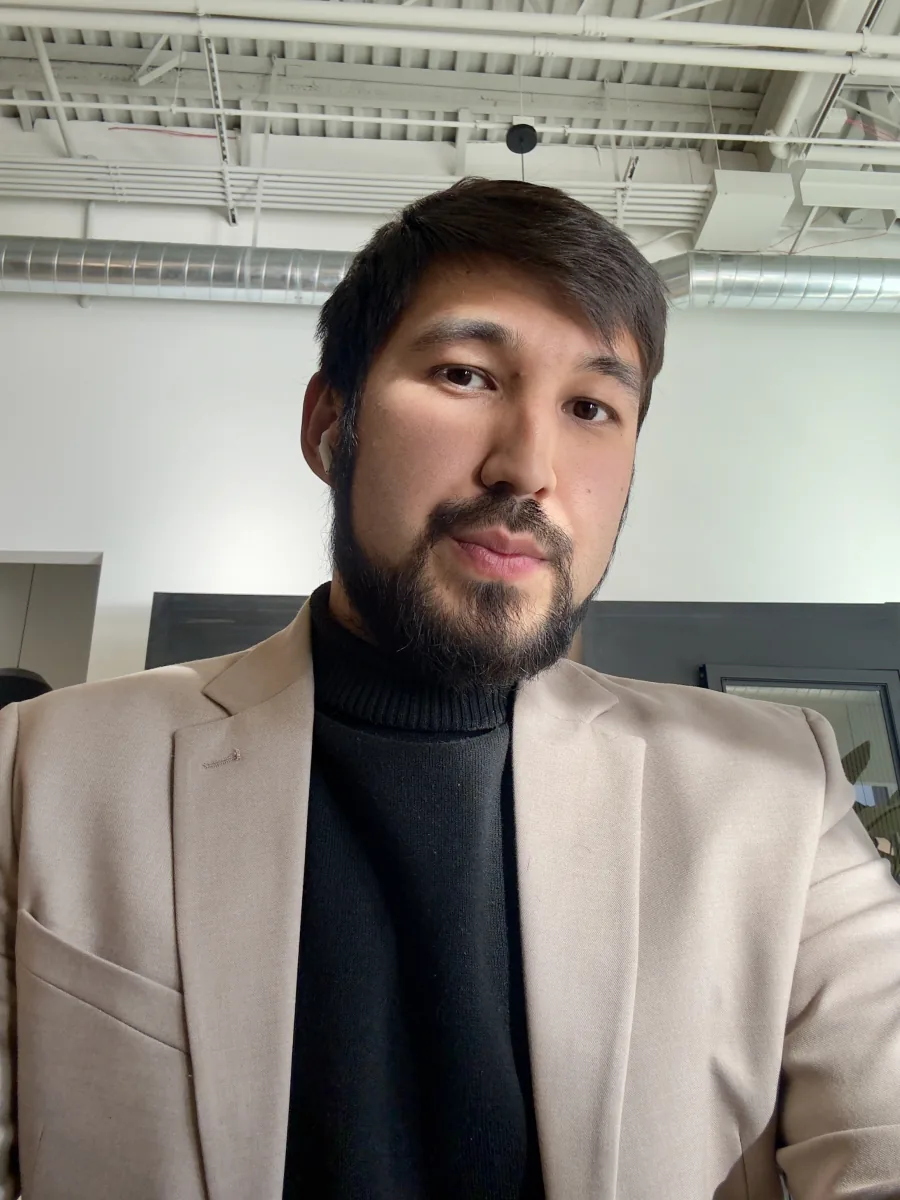 Portrait of Oybek Abdualiev in a beige blazer and black turtleneck
